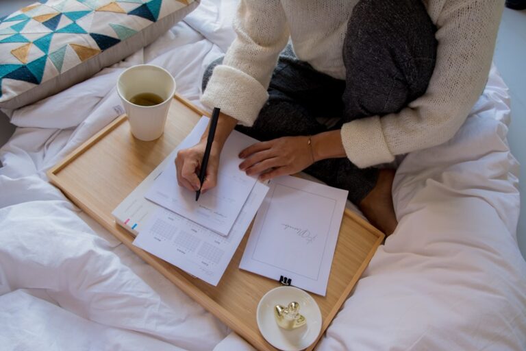 Young couple sits at a bright, modern dining table, looking thoughtfully over papers that could be mortgage documents or h...