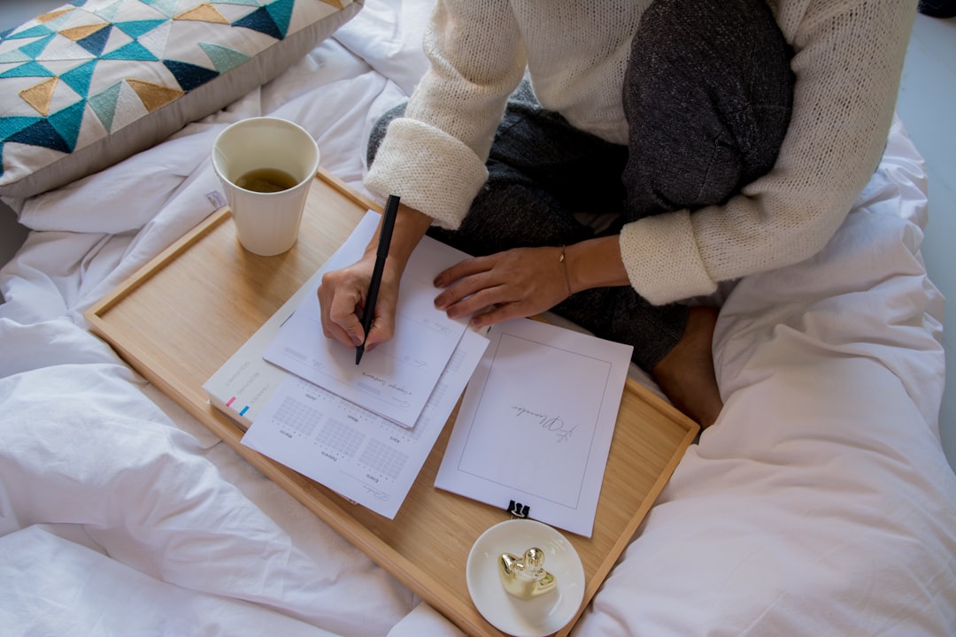 Young couple sits at a bright, modern dining table, looking thoughtfully over papers that could be mortgage documents or h...